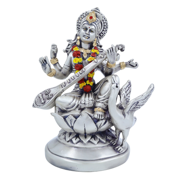 Silver-finish Saraswati idol holding veena with swan on lotus base decorated with garland – perfect for pooja and study room.